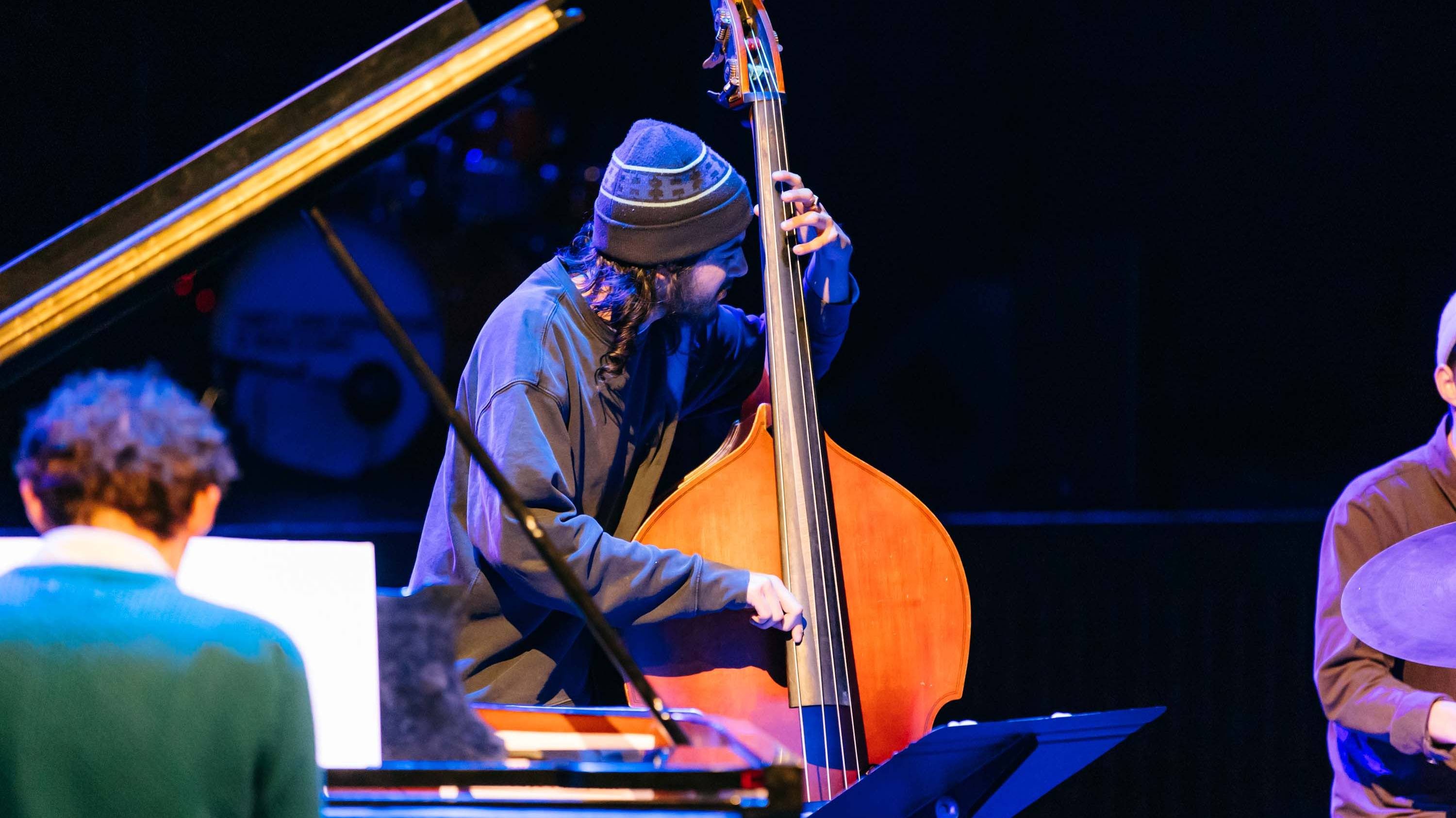 A student wearing a knitted hat plays a double bass