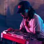 A student wears a baseball cap and plays a keyboard