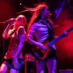 Two members of Soulstice perform on stage at Blackheath Halls. The person on the left is singing, and the person on the right is playing electric bass guitar.