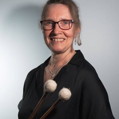 Kate is a white woman, she wears her hair tied back and has dark framed glasses.