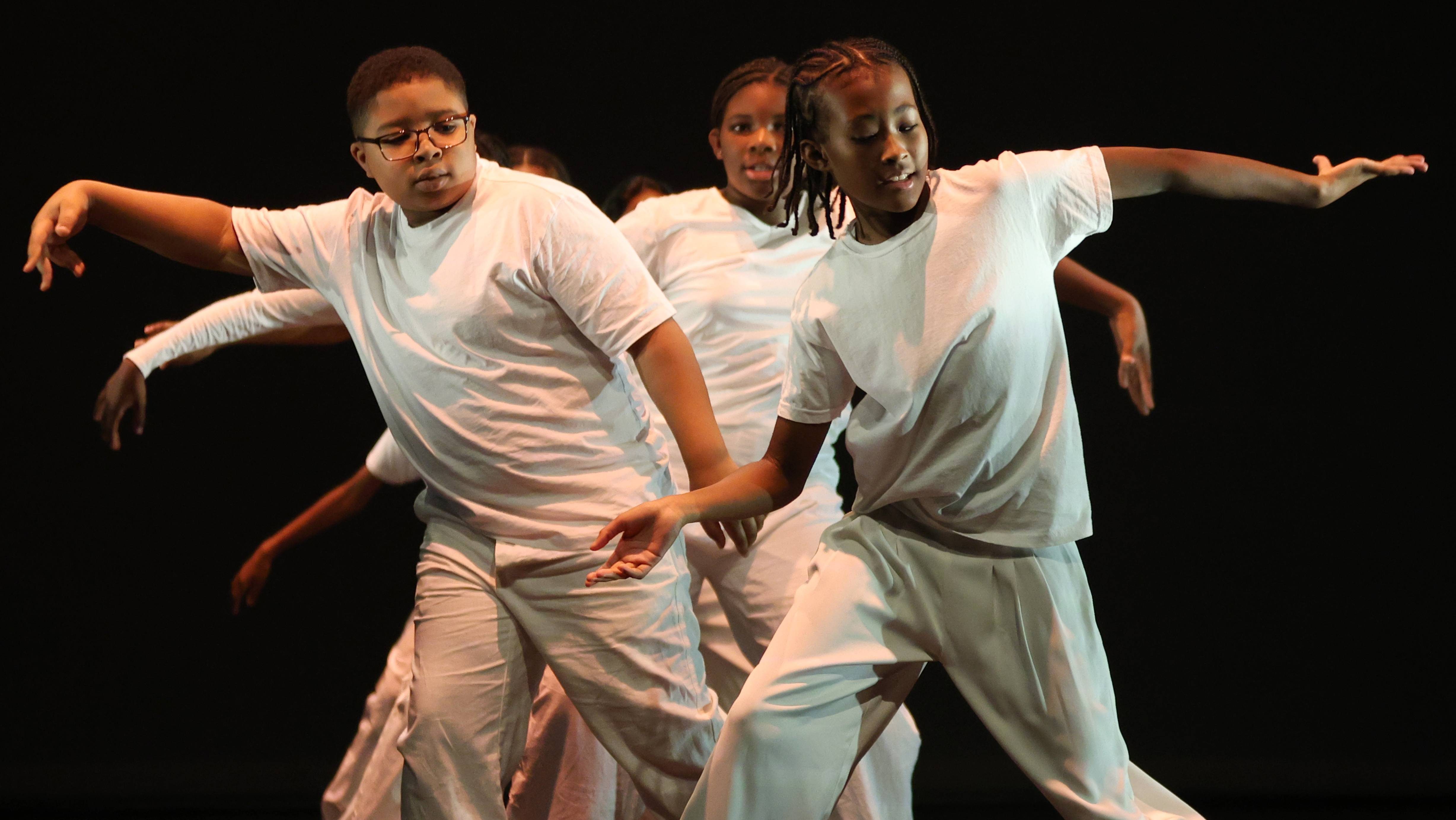 Young people hip-hop dancing on a stage, dressed in all white.