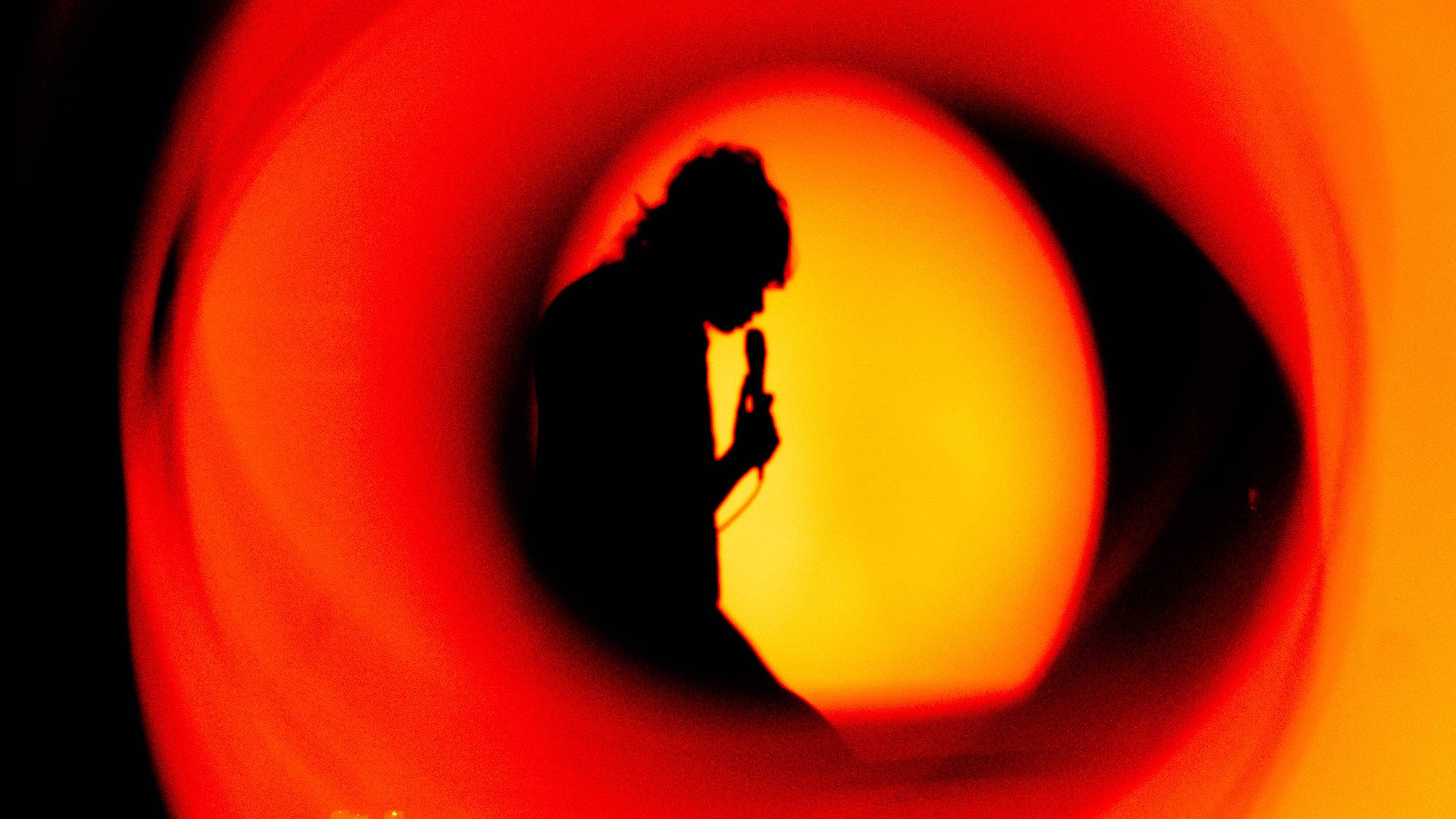 Silhouette of someone singing into a microphone.